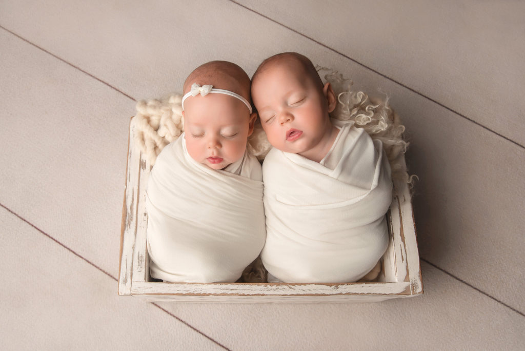 twin babies lay in wooden box in white wraps during Las Vegas Studio newborn portraits